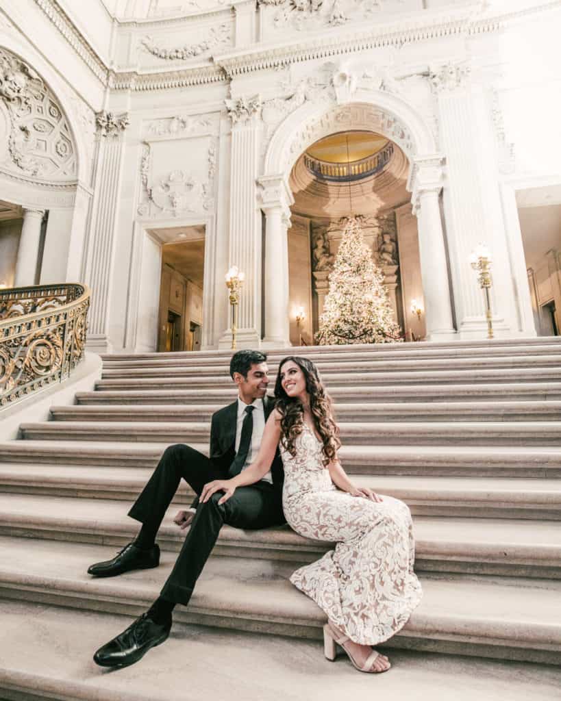 a couple sitting on the grand staircase by the Christmas tree