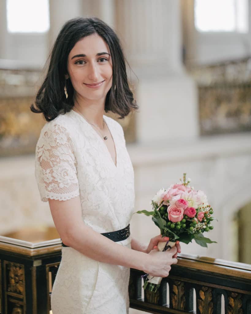 the bride in a jumpsuit style wedding gown posing on the Mayor's balcony