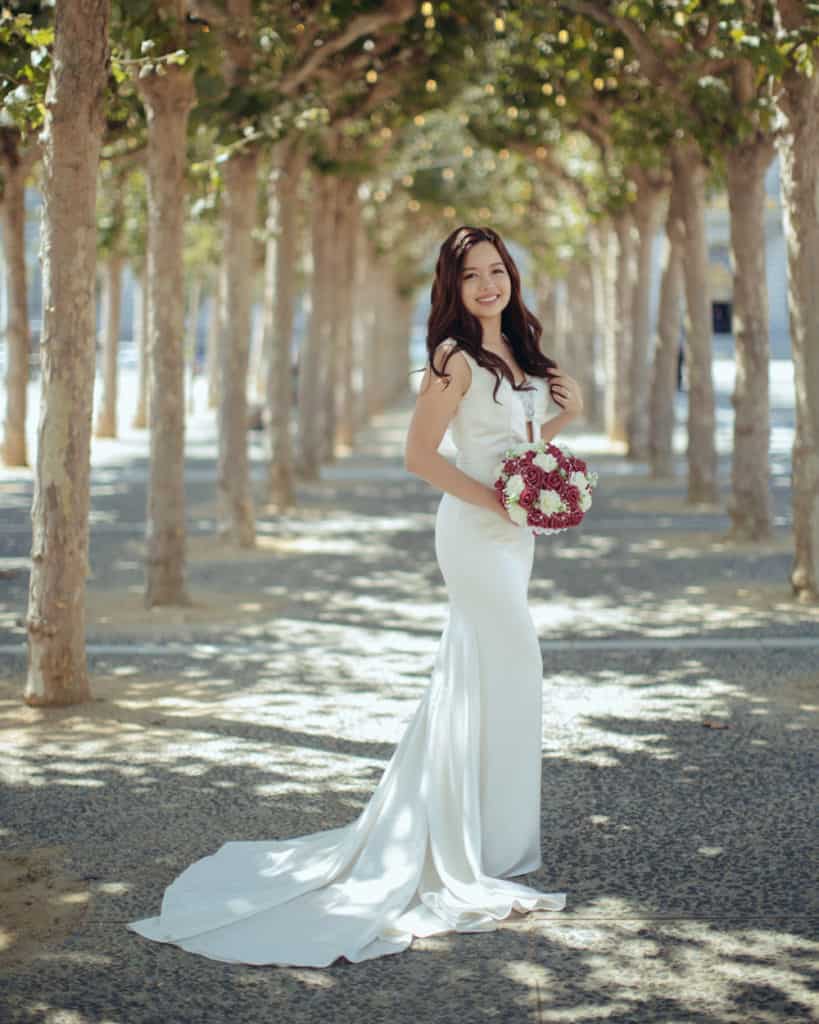 a bride posing in the tree tunnel across from city hall