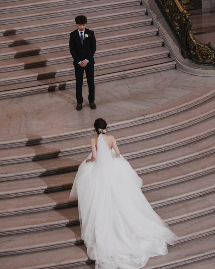 a bride walking up the grand staircase to meet the groom