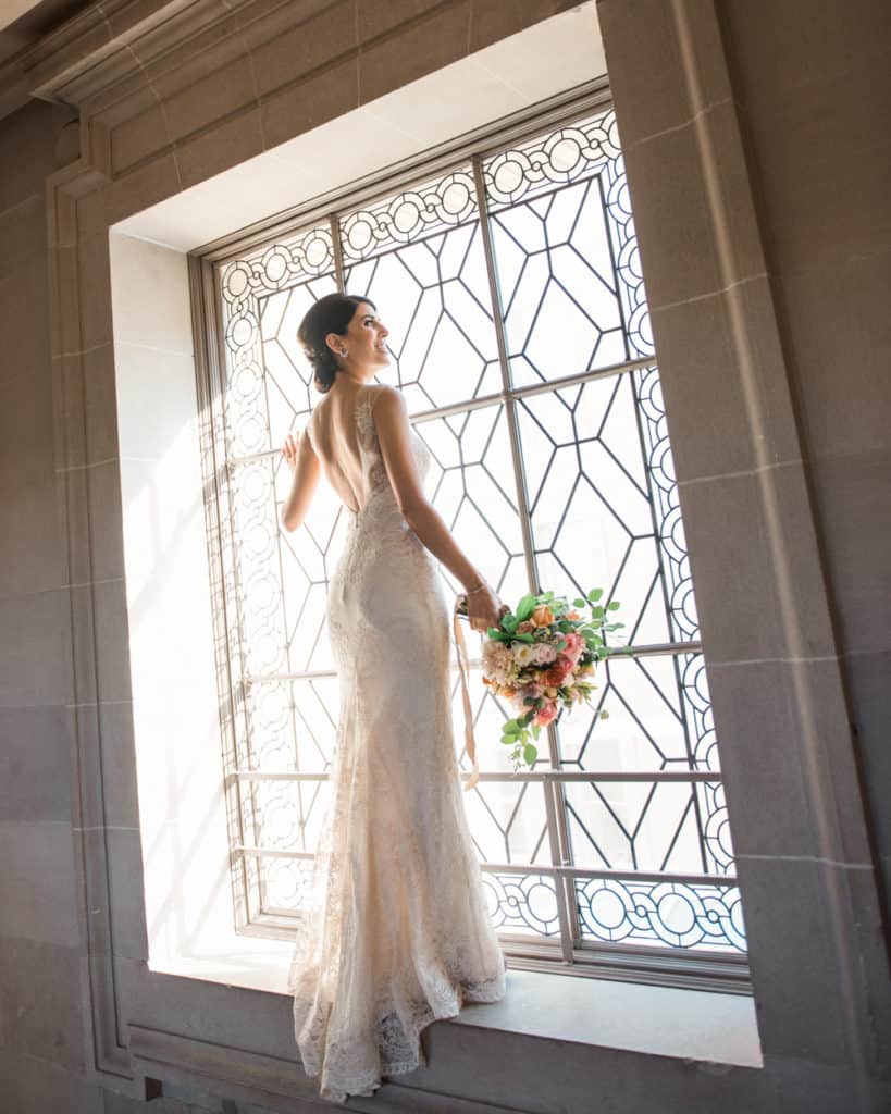 a bride posing on the 3rd froor by the window